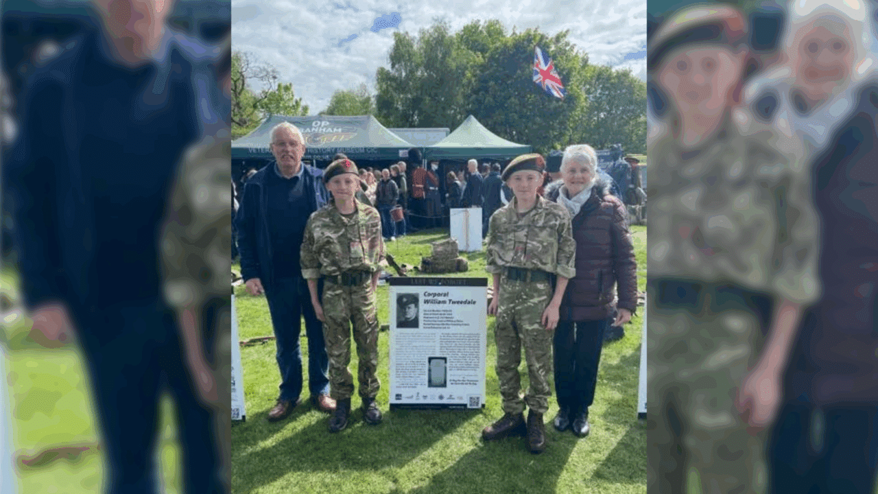 Cadets Charlie and Will Ferguson standing beside a biography board honouring their great-grandfather, Corporal William Tweedale, at VE80 Fest in Witton Park.