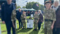Cadets Charlie and Will Ferguson standing beside a biography board honouring their great-grandfather, Corporal William Tweedale, at VE80 Fest in Witton Park.